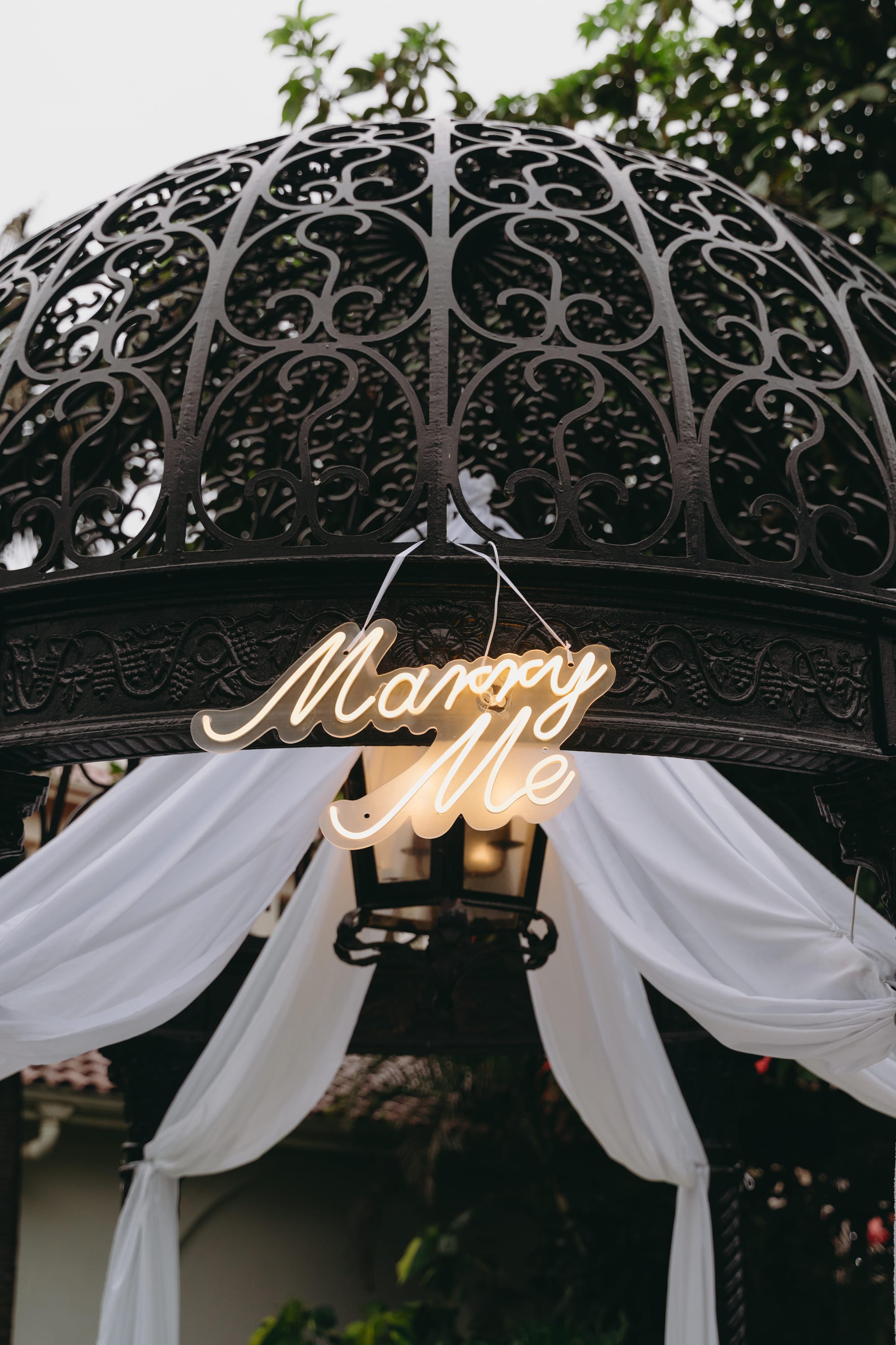 Neon &ldquo;Marry Me&rdquo; sign hanging in the gazebo